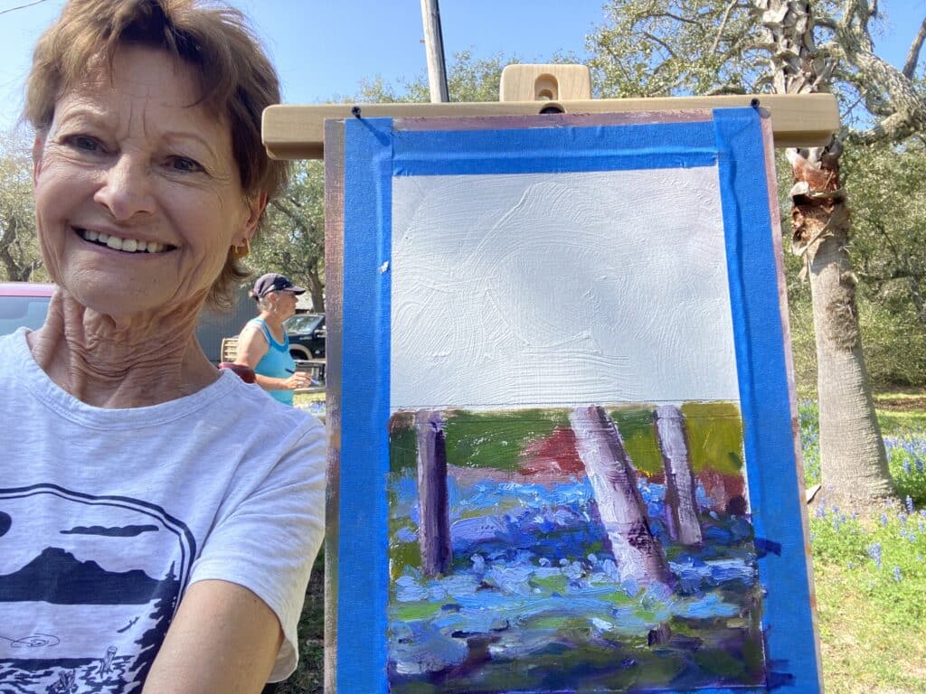 Photo of artist on location with an oil sketch of Texas bluebonnets.