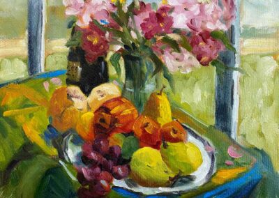 Oil still life painting in greens and reds of fruit, flowers and a view outside.